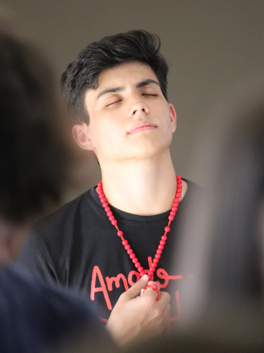 Guilherme, fundador da Uniclass, de olhos fechados segurando o terço durante um acampamento
